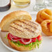 A Rastelli's turkey burger with onion rings on a plate.