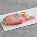A Rastelli's bone-in pork steak on a white surface.