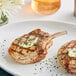 Two grilled Rastelli's bone-in pork steaks with butter on top on a white plate.