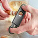 A person using a Franmara black cigar cutter to cut a cigar.