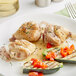 A white plate with cooked Rastelli's Chicken Osso Bucco, zucchini, and tomatoes.