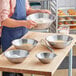 A man holding a Choice stainless steel mixing bowl filled with flour.