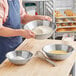 A man mixing dough in a stainless steel bowl.