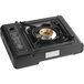 A black rectangular portable stove with a brass circular burner.