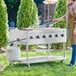 A woman cooking meat on a Backyard Pro stainless steel liquid propane outdoor grill in the grass.