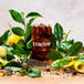 A glass of Tractor Beverage Co. Unsweet Tea with ice and lemons on a table surrounded by lemons and leaves.