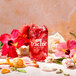 A glass bottle of Tractor Beverage Co. Organic Hibiscus Concentrate with red liquid and flowers on a table.