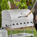 A woman standing next to an LPG48 grill with a Backyard Pro Roll Dome on a counter on an outdoor patio.