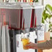 A person pouring Tractor Beverage Co. Organic Sweet Tea into a drink dispenser.