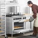 A man wearing a chef's hat using a Main Street Equipment Liquid Propane Range to bake cookies.