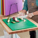 A woman cutting green vegetables on a purple Choice polyethylene cutting board.