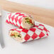 Two Choice red and white checkered deli wraps around a sandwich with turkey, cheese, and vegetables.