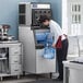 A man using an Avantco Air Cooled Modular Half Cube Ice Machine to fill a container with ice.