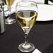 A Libbey Teardrop goblet filled with white wine on a table.
