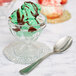 A Libbey glass bowl filled with green ice cream topped with chocolate syrup and a spoon.