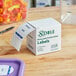 A white box of Noble Products 3" Product Date Round Removable Labels on a wooden table.