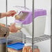 A person pouring brown sugar into a plastic container with a white lid.