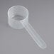 A clear plastic measuring scoop with a long handle.