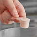 A hand using a 7.5 cc Polypropylene scoop to measure powder into a plastic container.