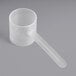 A clear plastic measuring cup with a long handle.