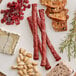 A plate with Shaffer Venison Farms hot venison snack sticks and cheese on a wood surface.