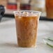 A clear compostable plastic cold cup filled with iced coffee.