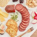 A plate with Shaffer Venison Farms venison summer sausage, cheese, nuts, and bread.