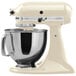 A white KitchenAid Artisan stand mixer with a silver bowl.