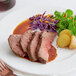 A plate of Shaffer Venison Farms boneless venison shoulder roast with potatoes and vegetables.