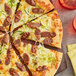 A pizza with sausage and zucchini on a wooden board.