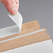 A person putting a piece of paper in a white rigid mailer.
