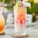 A table with 2 Tiki glasses filled with red and white drinks, ice, and fruit.