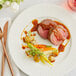 A plate with Shaffer Venison Farms Boneless Backstrap Venison Loin Roast and vegetables with a fork and knife.