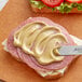 A sandwich with Esprit de Paris Dijon Mustard on a white counter.