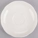 A CAC ivory scalloped edge saucer with a circle on a gray surface.