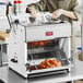 A man using an Estella countertop bread slicer in a professional kitchen.