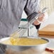 A person using a Choice 16" Stainless Steel French Whisk to mix batter in a bowl.