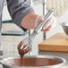 A person using a Choice stainless steel French whisk to mix chocolate batter in a bowl.