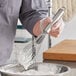 A person using a Choice 12" stainless steel piano whisk to mix ingredients in a bowl.