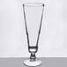 A Libbey footed pilsner glass with a curved tip on a table.