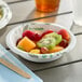 A Dixie Ultra Pathways paper bowl filled with fruit on a table.