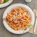 A Dixie Ultra paper plate with pasta, sauce, and cheese.