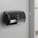 A black Compact by GP Pro double coreless roll toilet paper dispenser on a wall.