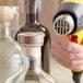 A hand using a blow dryer to shrink a clear perforated shrink band on a bottle.