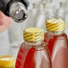 A close-up of a person using a 1" non-perforated shrink band to seal a bottle of liquid.