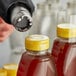 A close-up of a clear shrink band on a bottle of liquid being poured into a jar.