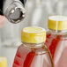 A person using a clear shrink band to seal a jar of liquid.