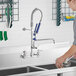 A woman using a Waterloo pre-rinse faucet to wash dishes in a kitchen sink.