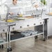 A man standing in front of a ServIt steam table with a sneeze guard.