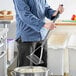 A man using a Fourt&#233; chrome plated square-faced potato masher to mash potatoes in a white bowl.